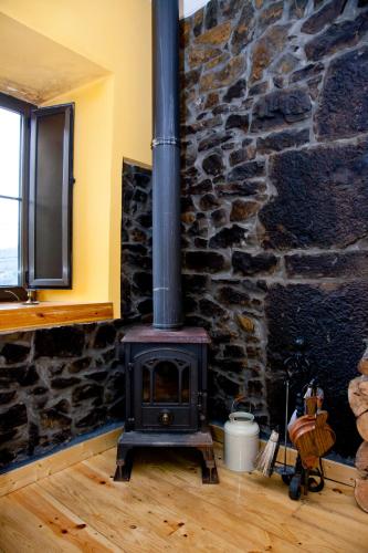 a fireplace in a room with a stone wall at La casa'l cantirín in Pola de Lena