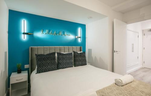 a bedroom with a large bed with a blue wall at Town Centre apartment with private patio - Near Airport & Train Station in Luton