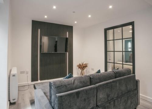 a living room with a couch and a large window at Town Centre apartment with private patio - Near Airport & Train Station in Luton