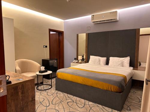 a hotel room with a large bed and a chair at لامار بارك للأجنحة الفندقية in Tabuk