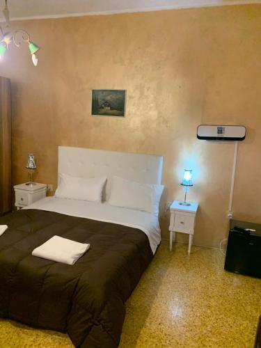 a bedroom with a large bed and a night stand with a lamp at PRINCIPE ROOMS in Rodigo