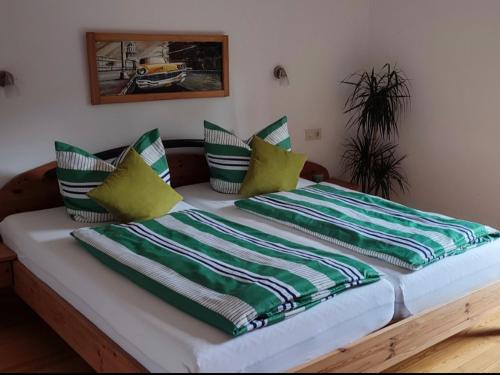 ein Bett mit grünen und weißen Kissen darauf in der Unterkunft Ferienwohnung Gabriel in Bad Kohlgrub