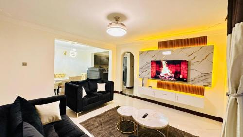 Una sala de estar con un sofá y un televisor. en Serenity LakeView 4BR Duplex Entebbe Close to Airport, en Entebbe