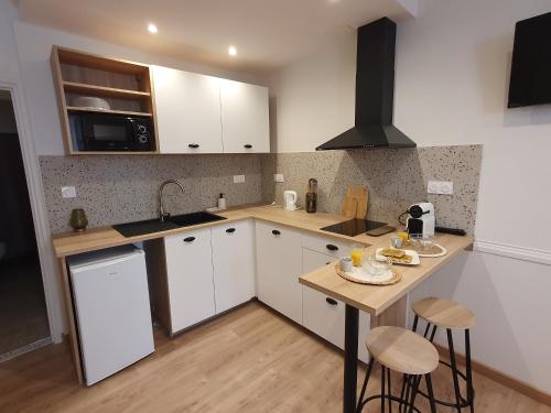 une cuisine avec des armoires blanches et un comptoir en bois dans l'établissement Appartement Ô Arcades, à Lisle-sur-Tarn