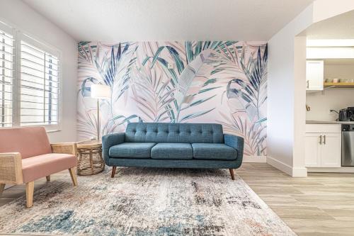 a blue couch in a living room with a tropical wallpaper at One bedroom unit near Epic Universe and Universal, free parking in Orlando