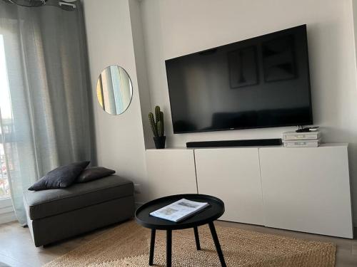 a living room with a tv on a white cabinet at Appart Cosy emplacement N1 Théâtre in Cherbourg en Cotentin