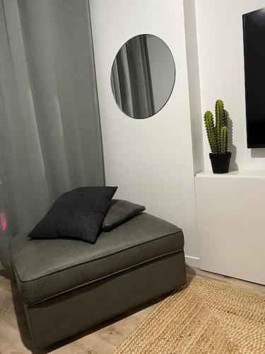 une chaise avec un miroir sur un mur avec un cactus dans l'établissement Appart Cosy emplacement N1 Théâtre, à Cherbourg en Cotentin