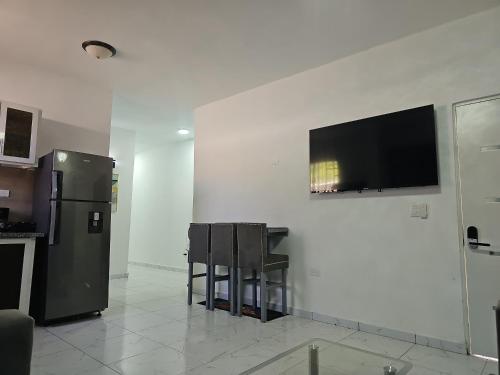 a kitchen with a table and a television on a wall at Victor Malecon 1B in San Pedro de Macorís