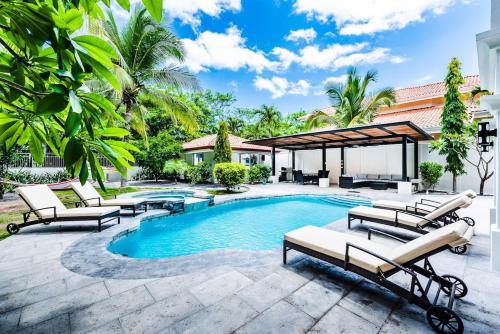 a swimming pool with chaise lounges and chairs around it at Barefoot Beachfront, Pool, Surf & Private Casita in Playa Grande