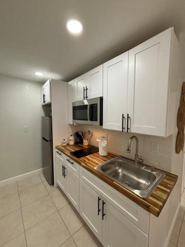 a kitchen with white cabinets and a stainless steel sink at VillaBellaWood in Fort Myers