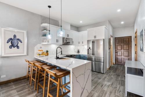 a kitchen with white cabinets and a island with bar stools at Charming 2BR - 2BA Condo Steps to the Beach in Tamarindo