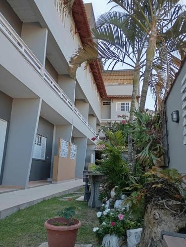 a side view of a building with palm trees and flowers at Pousada Tortuga in Anchieta