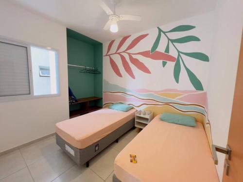 two beds in a room with a painting on the wall at Apê Jardins 212 - Piscina, Churrasqueira, 2 Quartos a 600m da Orla Central in Ubatuba