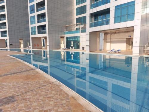 a large swimming pool in front of a building at Sunset Sea view Furnish Apartment in Ajman 