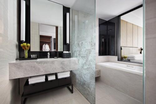 a bathroom with a sink and a tub and a mirror at Bangkok Marriott Hotel The Surawongse in Bangkok