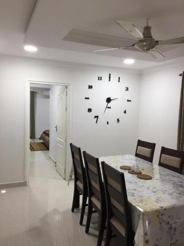 a dining room with a table and a clock on the wall at Luxurious 2 bedroom apartment in Thiruvalla town in Thiruvalla