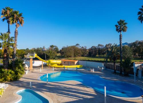 - une piscine dans un complexe avec toboggan et palmiers dans l'établissement MOBIL-HOME d'Anne et Edouard, à Argelès-sur-Mer