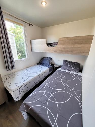 une chambre avec deux lits et un lit superposé dans l'établissement MOBIL-HOME d'Anne et Edouard, à Argelès-sur-Mer