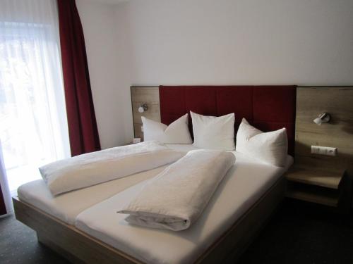 a bedroom with a large bed with white sheets and pillows at Appartements Kroner in Nauders