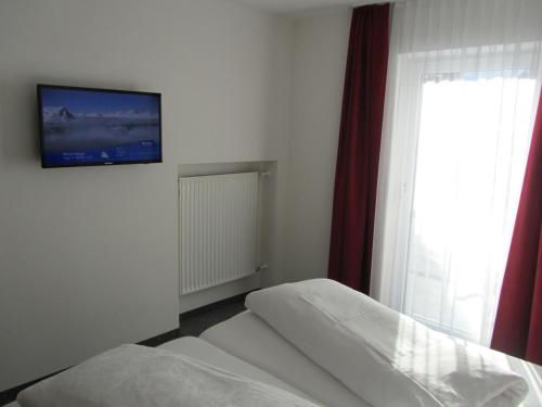 a bedroom with two beds and a tv on the wall at Appartements Kroner in Nauders