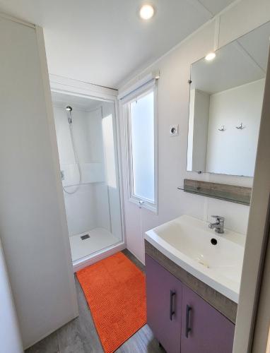 une salle de bain blanche avec un lavabo et un miroir dans l'établissement MOBIL-HOME d'Anne et Edouard, à Argelès-sur-Mer
