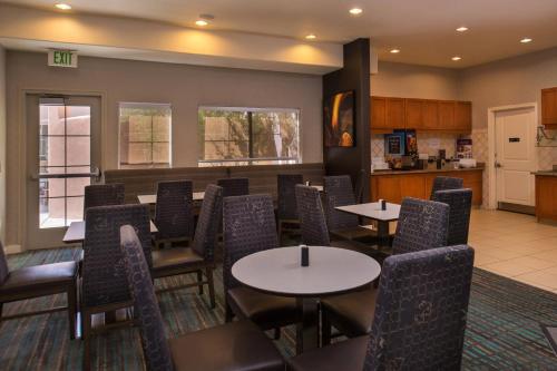 a dining room with tables and chairs and a kitchen at Residence Inn by Marriott Albuquerque Airport in Albuquerque
