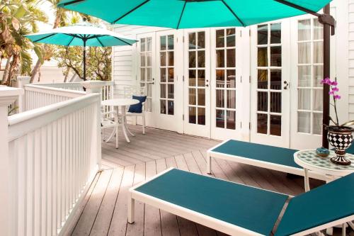 a patio with tables and umbrellas on a deck at The Gardens Hotel in Key West