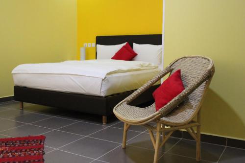 a bedroom with a bed and a chair with red pillows at Auberge Tinit in Er Rachidia