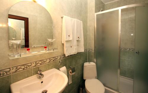 een badkamer met een wastafel, een toilet en een spiegel bij Hotel Alafrangite in Plovdiv