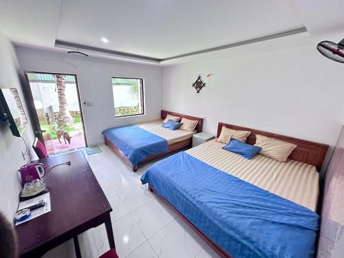 a bedroom with two beds and a desk and a television at AN THINH Hotel & Homestay in Bình Tú