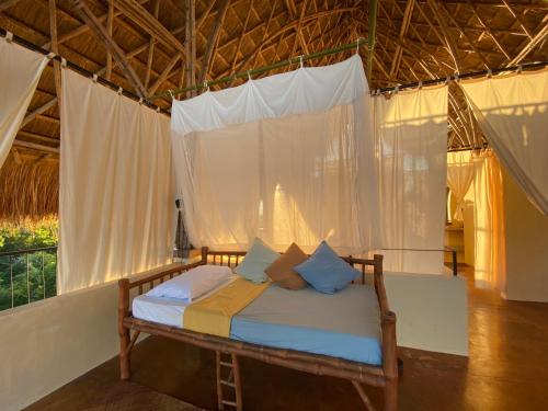a bed in a room with white curtains at Butanding Barrio Villa in Puerto Princesa City