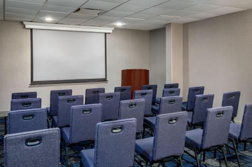 an empty room with blue chairs and a white screen at Courtyard Boston Marlborough in Marlborough