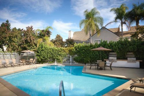 a swimming pool in a yard with chairs and umbrellas at Residence Inn Sunnyvale Silicon Valley II in Sunnyvale
