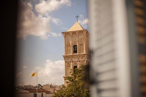 a clock tower with a flag on top of it at Hotel Opera in Larnaca