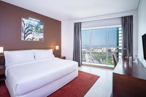 ein Hotelzimmer mit einem Bett, einem Schreibtisch und einem Fenster in der Unterkunft Four Points by Sheraton Sharjah in Schardscha