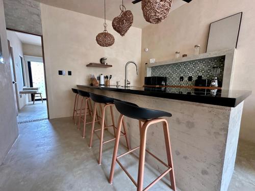 a kitchen with a counter with stools at a bar at Chichén 27 Departamentos nuevos con piscina cerca de Ferry a Isla Mujeres in Cancún