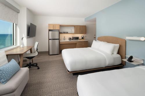a hotel room with two beds and a desk at Element Melbourne Oceanfront in Melbourne