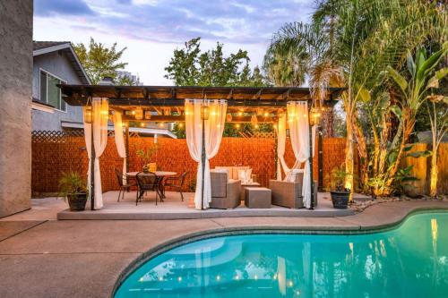 a pergola with a table and chairs next to a pool at Chic Boho 3BR Home Near Woodward Park in Fresno