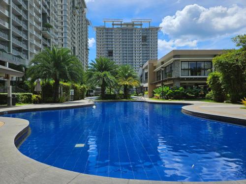 a large blue swimming pool with buildings in the background at Verdon Parc Haven Cozy Condo in Ecoland, Davao in Davao City