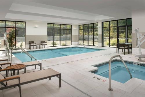 a large swimming pool with tables and chairs and windows at Courtyard Portland East in Portland