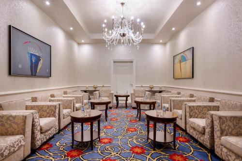 a waiting room with chairs and tables and a chandelier at JW Marriott Marquis City Center Doha in Doha