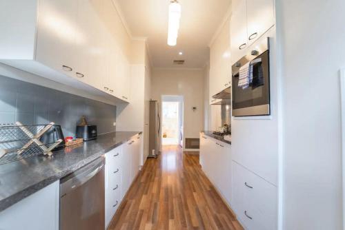a kitchen with white cabinets and a wooden floor at Cambridge House, Bendigo in Bendigo