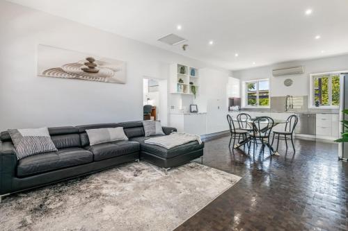 a living room with a black couch and a kitchen at Bayne St Studio in Bendigo