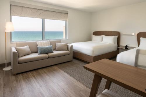 a hotel room with a couch and a bed and a window at Element Melbourne Oceanfront in Melbourne