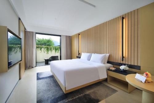 阳朔Guilin Yangshuo Nine Roots Luxury Hotel的卧室里有一张白色的大床和一张书桌