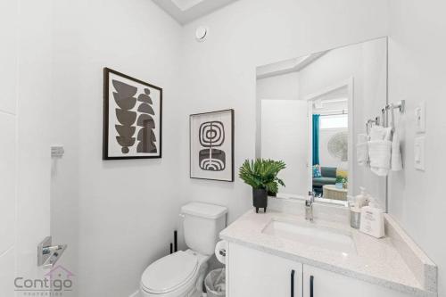 a white bathroom with a toilet and a sink at Urban Jungle Getaway, AirCon, 10min to DT & WEM! in Edmonton