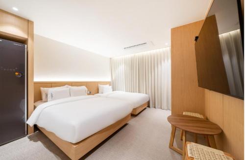 a bedroom with a large white bed and a television at H avenue Hotel Jeonju Deokjin in Jeonju