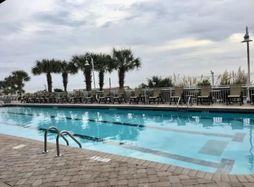 a large swimming pool with chairs and palm trees at Paradise Resort in Myrtle Beach