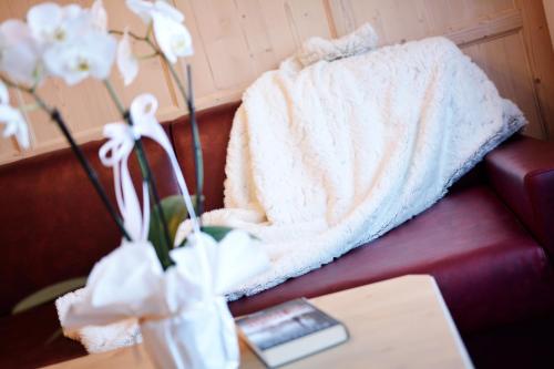 a blanket on a couch with flowers on a table at Residence Isabell in Selva di Val Gardena