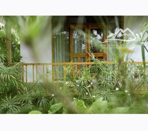 a garden with plants in front of a building at Bakhan Village Resort in Mai Chau